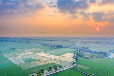 Aerial view of agricultural landscape against sky during sunset