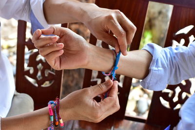 Cropped image of man tying bracelet on woman hand