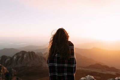 Rear view of person standing on mountain against sky