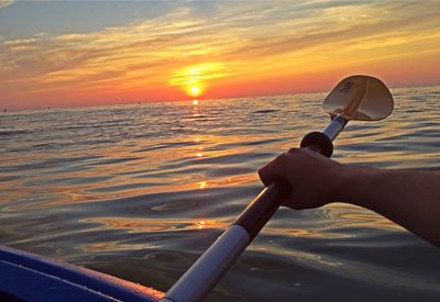 Cropped image of man photographing sea at sunset