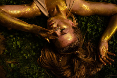 Young woman in gold lies on the grass