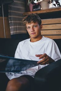 Handsome young man sitting on sofa with magazine