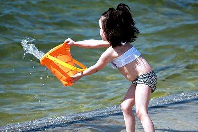 Little girl throwing water back into the ocean