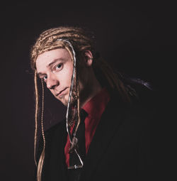 Portrait of mid adult man with blond hair standing against black background