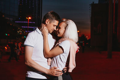Young couple standing in city at night