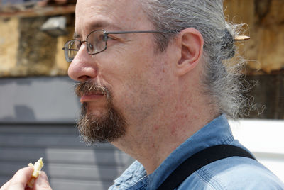 Side view of mature man looking away while standing outdoors