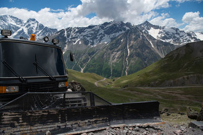 A black grader stands in the mountains in summer.  ratrak, a machine for paving roads in the snow