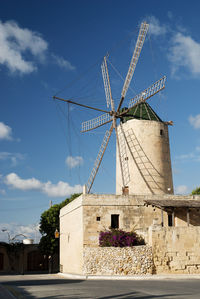 Traditional windmill by building against sky