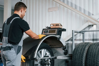 Fixing the tire. man in uniform is working in the auto service.