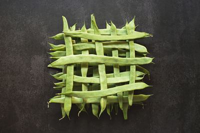 Top view of whole green beans in a geometric pattern on dark background