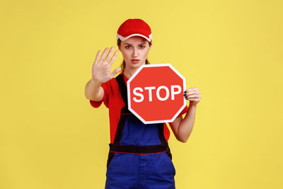 Portrait of young woman holding paper against yellow background