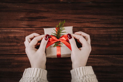 Cropped hands of woman holding gift on table