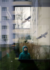 Boy reflecting on glass building