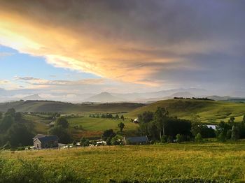 Scenic view of agricultural field against sky at sunset