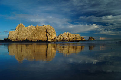 Rock formations by sea against sky