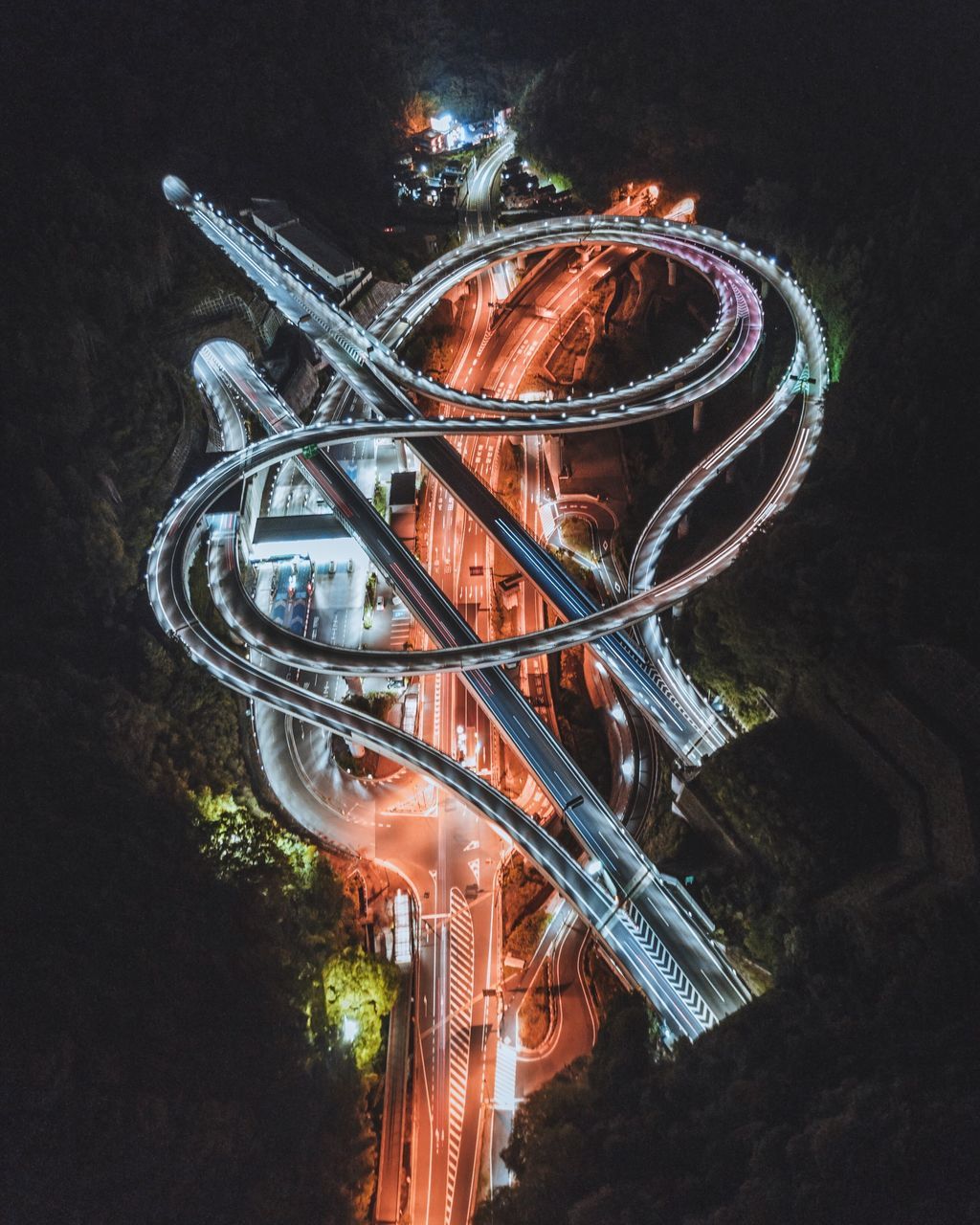 illuminated, night, no people, motion, architecture, low angle view, tree, nature, built structure, orange color, amusement park ride, lighting equipment, outdoors, long exposure, amusement park, blurred motion, glowing, celebration, chain swing ride, metal