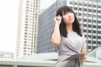 Young businesswoman standing against buildings in city