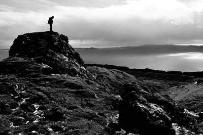 Silhouette man standing on cliff against sky