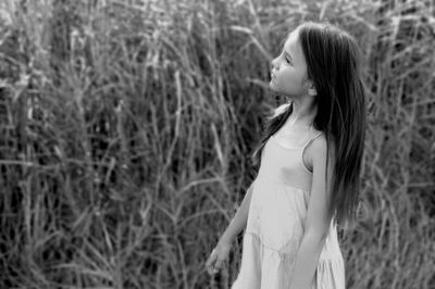 Girl looking away while standing by plants