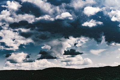 Low angle view of cloudy sky over silhouette landscape