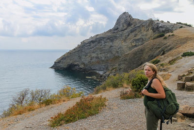 Side view of woman looking at sea against sky