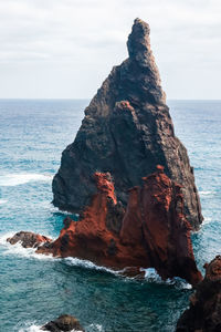 Rock formation in sea against sky