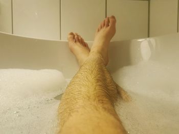 Low section of man relaxing in bathroom