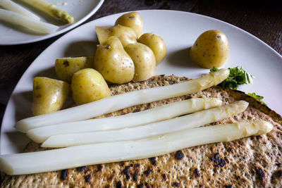 Close-up of asparagus and pancakes by potatoes in plate