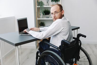 Side view of man using digital tablet while sitting on table