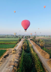 Hot air balloon flying over field against sky