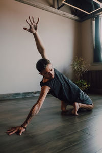 Diligent barefooted athlete in sportswear practicing yoga on wooden floor in spacious contemporary workout room