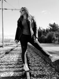 Full length of woman standing on railroad track against sky