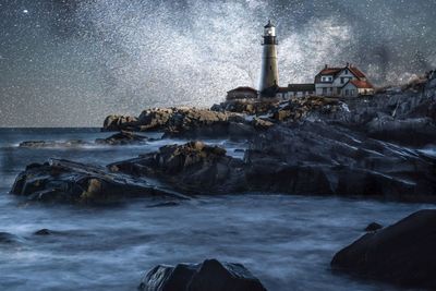 Water splashing on rocks by sea against sky