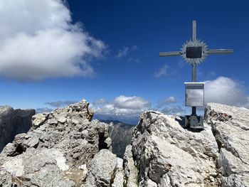 Low angle view of cross on rock against sky