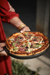 Cropped hand of person holding pizza