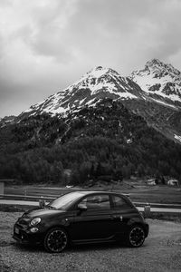 Cars on road against snowcapped mountains against sky