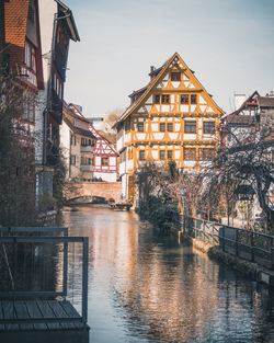 Buildings by river against sky in city