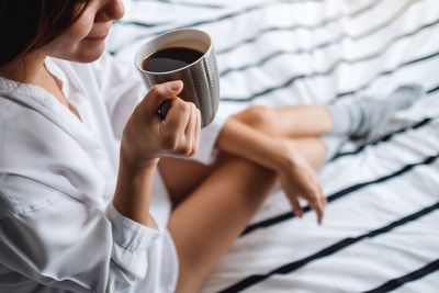 Midsection of woman holding coffee cup at home