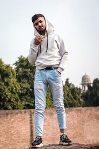 Low angle portrait of young man standing against clear sky