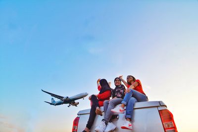 Low angle view of people sitting on airplane against sky