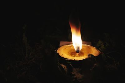 Close-up of lit candle in the dark