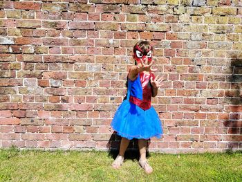 Portrait of girl in costume standing against brick wall