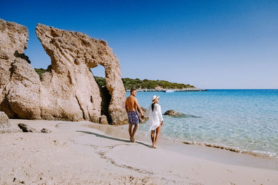 People at beach against clear sky
