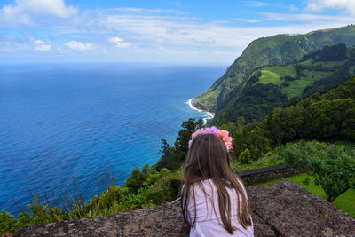 Rear view of girl looking at sea against sky