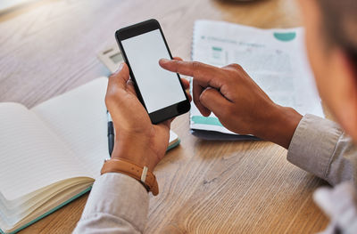 Midsection of man using mobile phone on table