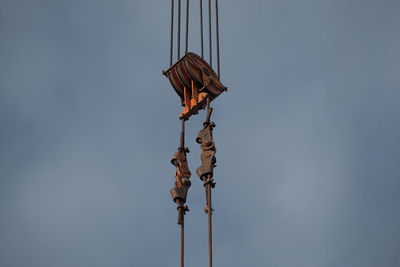 Low angle view of crane pulley against cloudy sky