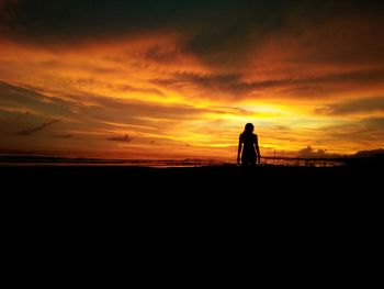 Silhouette man photographing on landscape against sky during sunset