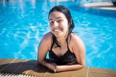 Young brunette teen girl posing in blue swimming pool in a hotel in turkey
