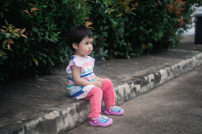 Full length of cute girl sitting outdoors