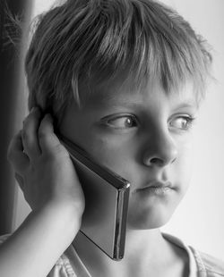 Close-up portrait of boy holding mobile phone